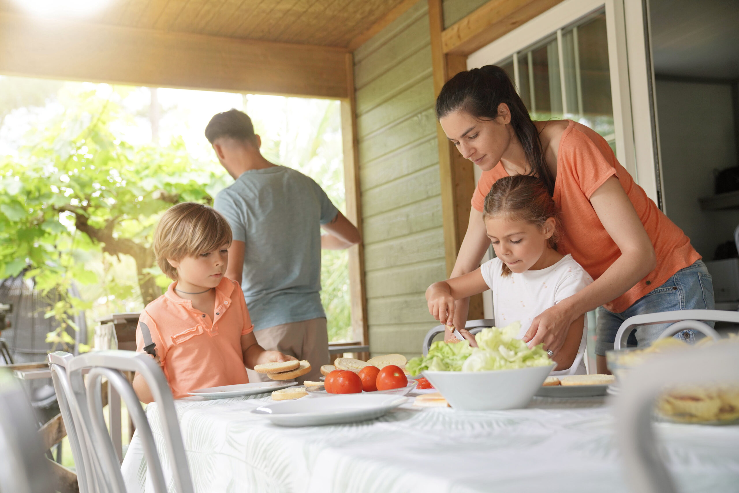 mom, dad and kids enjoying an outdoor lunch on their backyard patio